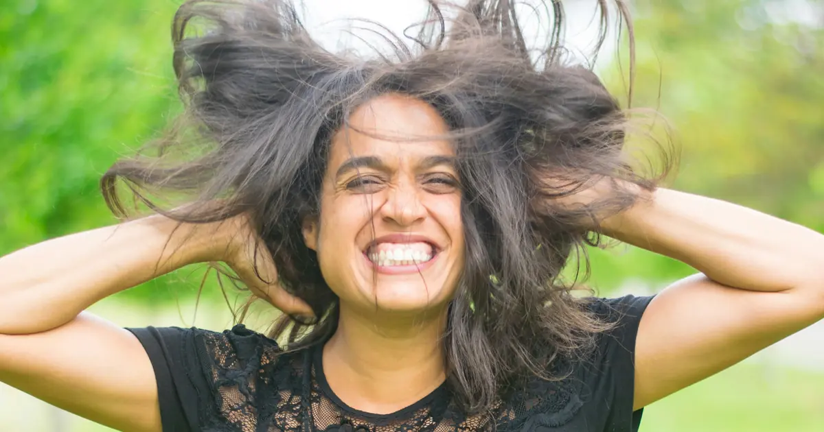 A young Indian woman laughing freely with her hair caught in the wind — ManaSmurti on the lightness of putting feelings into words.